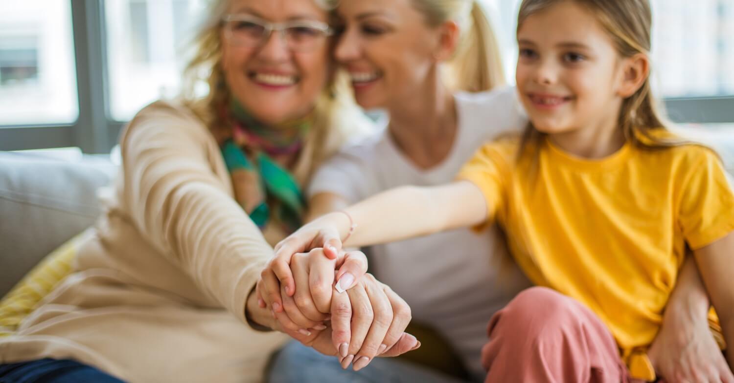 3 Frauen: Großmutter, Mutter und Tochter bzw Enkeltochter reichen sich die Hand